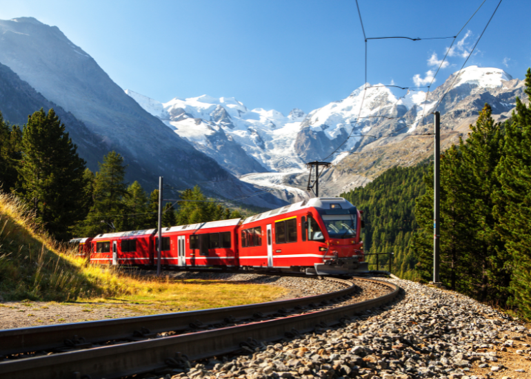 Red train winding through snowcapped alps of Switzerland
