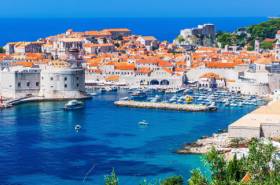 Croatia Travel Advice: How much does it cost to travel Croatia like a Travel Guide? Image shows blue oceans and ancient city of Dubrovnik, Croatia.